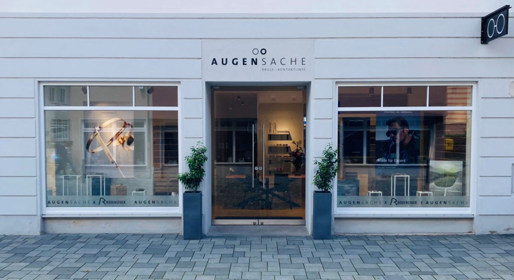 Die freundliche Ladenfassade von Augensache Brille Kontaktlinse in der Friedberger Innenstadt. Die großen Schaufenster zeigen eine aktuelle Dekoration von Rodenstock und laden zum Reinkommen ein.